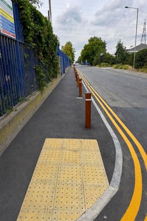 New timber bollards and tactile paving along the reinstated footway beside the fenced street in Barking, East London