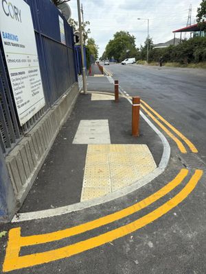 Completed footway with tactile paving, timber bollards, and fresh yellow lining outside Cory's Barking Transfer Station in East London