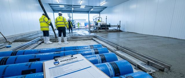 Food manufacturing facility groundworks - concrete slab pour with drainage channels and workers in hi-vis