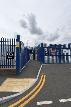 Pedestrian entrance with new tactile paving, reinstated footway, and fresh double yellow lines at the blue security gates in Barking